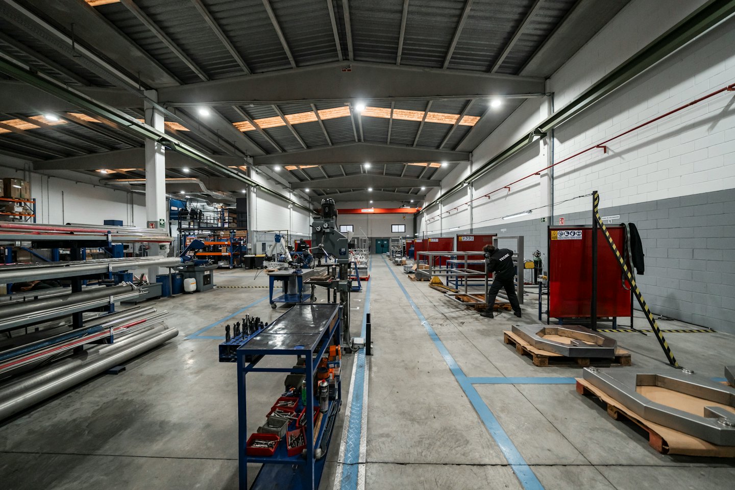 Worker assembling metal components on a pallet in a workshop.