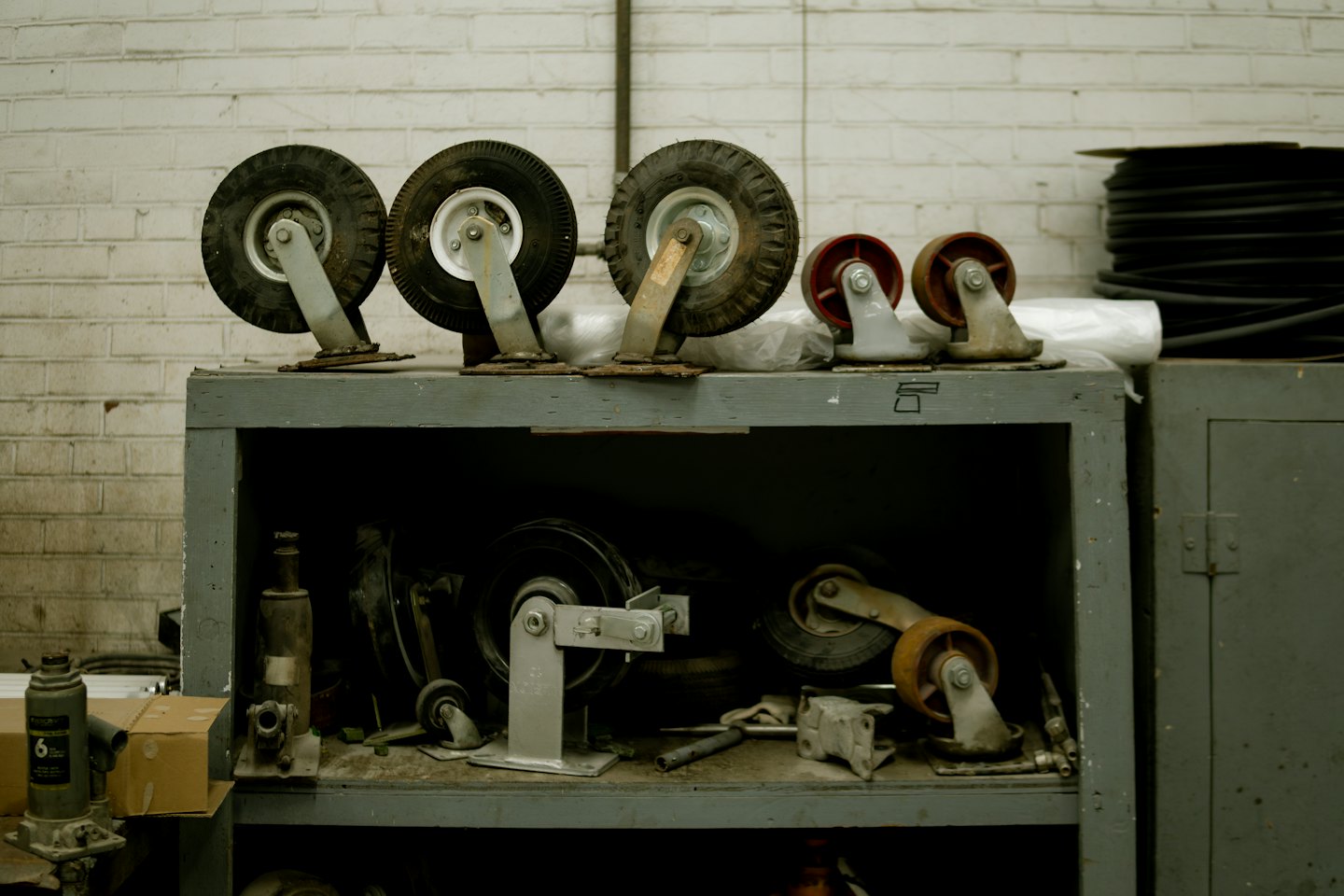 Industrial wheels and casters stored on a metal shelf unit.